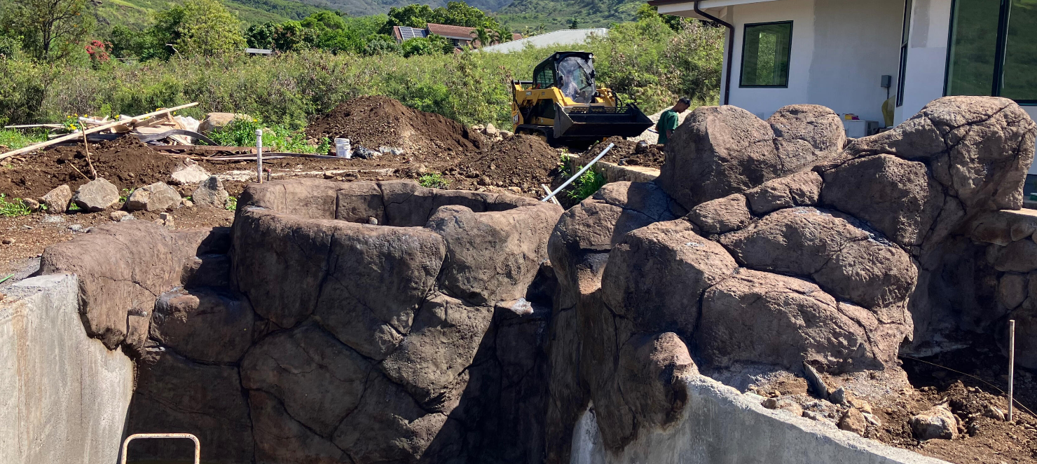 Sculpted concrete boulders and rockwork around a pool under construction